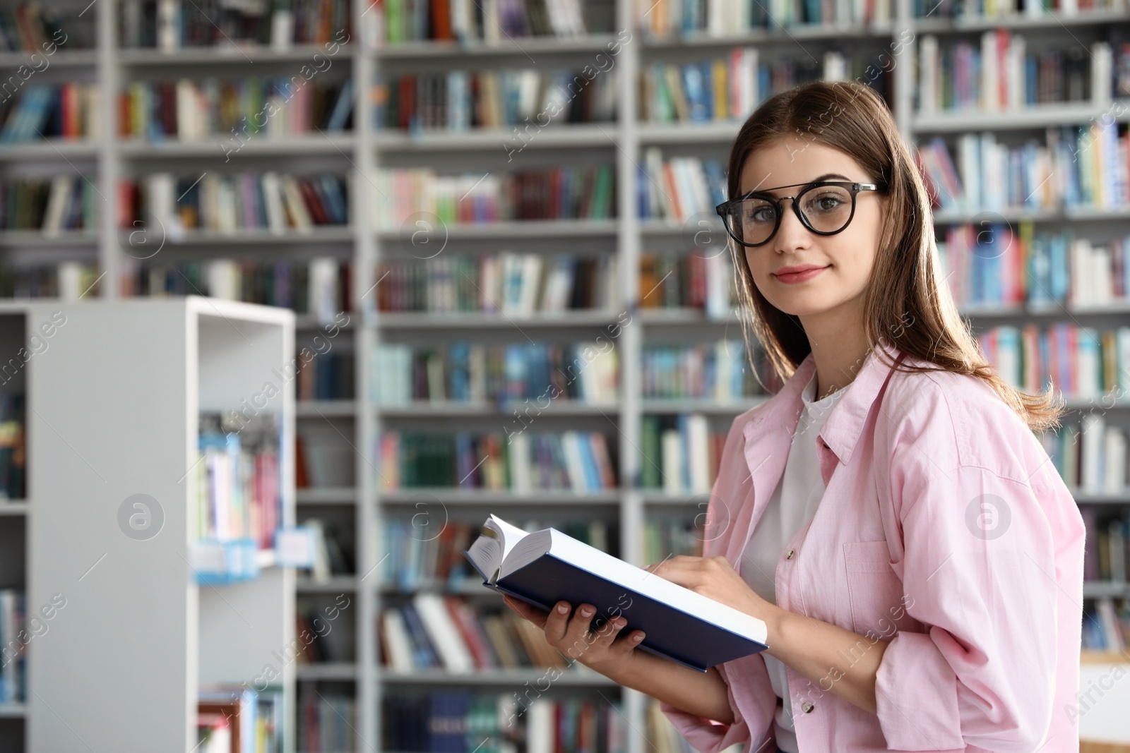 Photo of Young beautiful woman with book in library