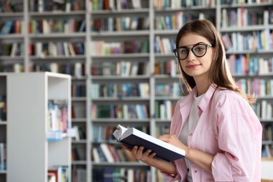 Young beautiful woman with book in library