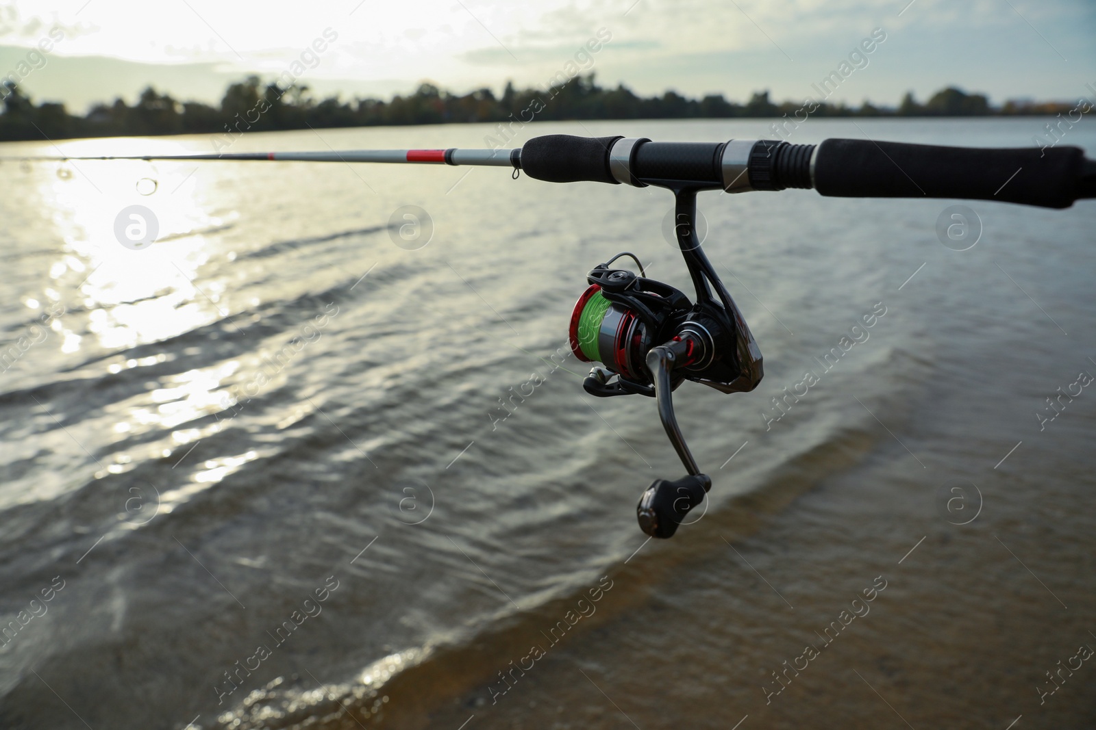 Photo of Fishing rod with reel near river, space for text