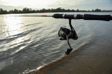 Photo of Fishing rod with reel near river, space for text