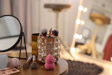 Different beauty products and mirror on wooden table in makeup room, space for text