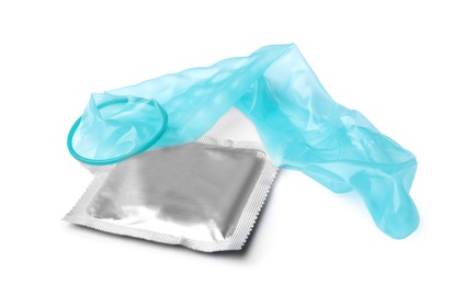 Unrolled light blue condom and package on white background. Safe sex