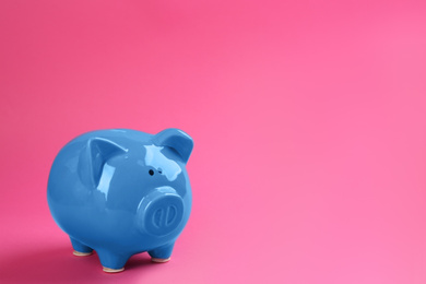 Blue piggy bank on pink background. Space for text