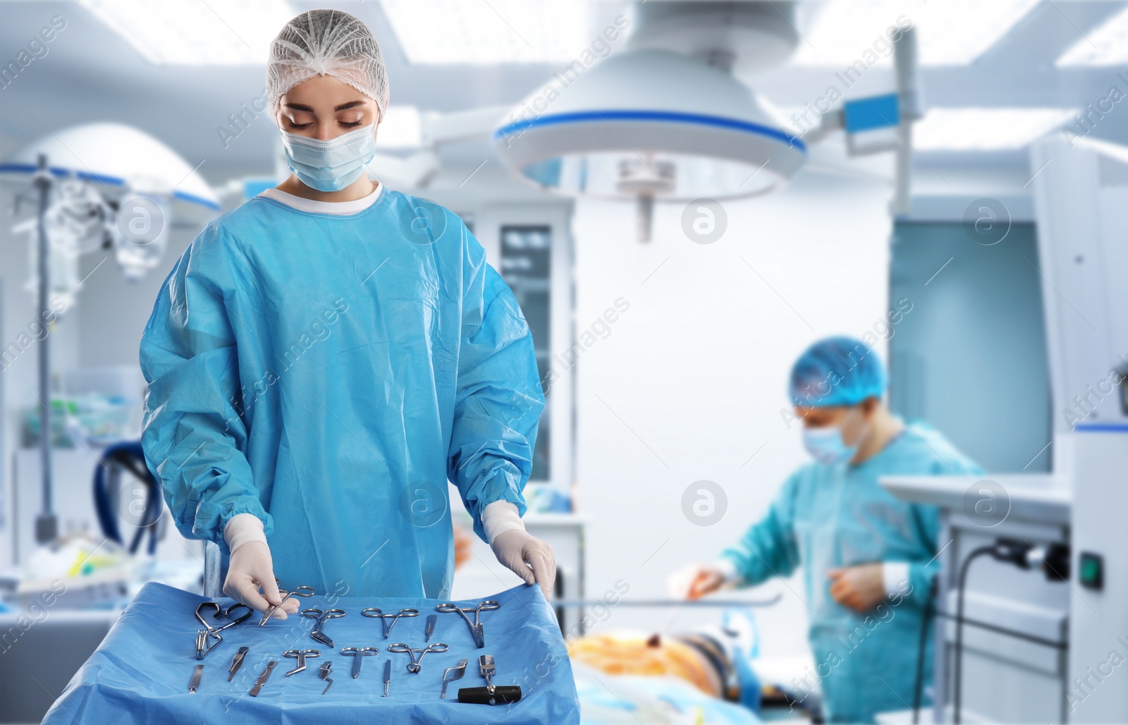 Image of Nurse near table with different surgical instruments in operating room