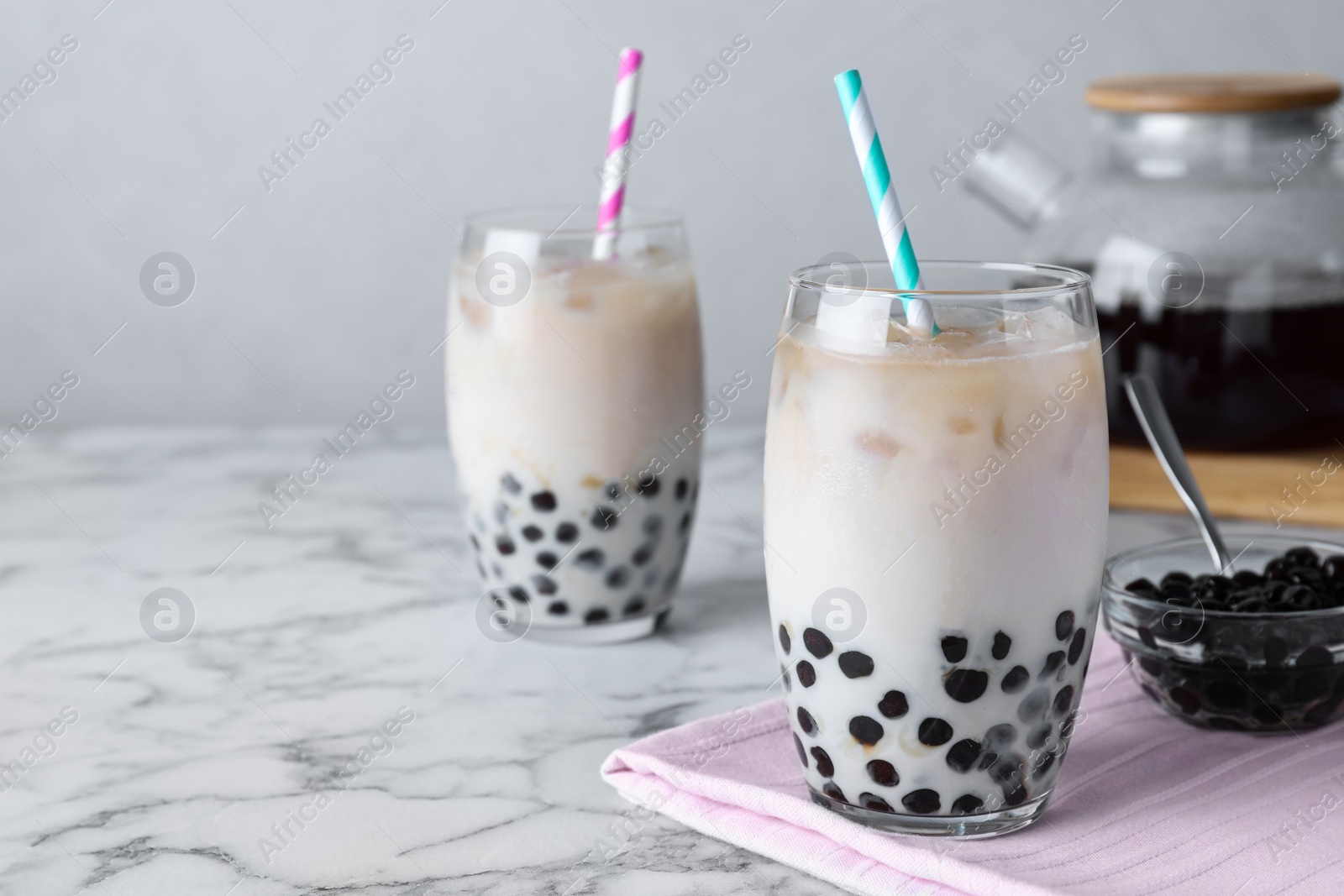 Photo of Bubble milk tea with tapioca balls on white marble table. Space for text