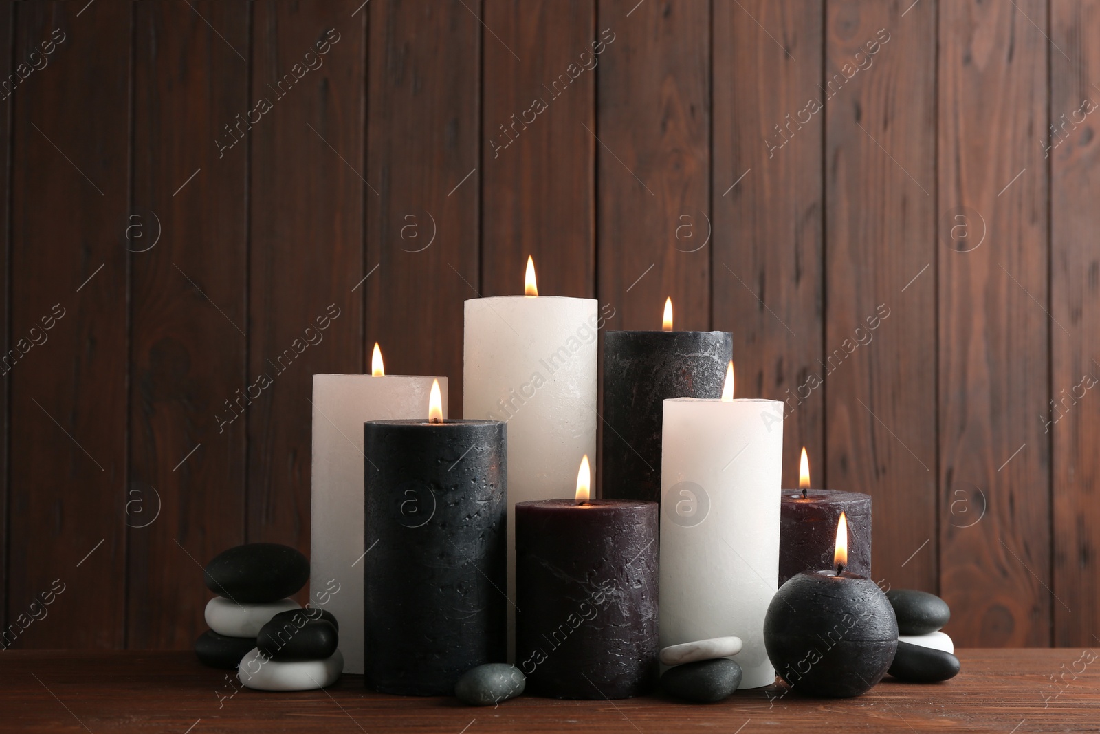 Photo of Composition with burning candles on table against wooden background