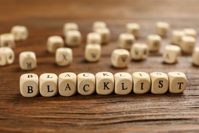 Photo of Cubes with word Blacklist on wooden table, closeup