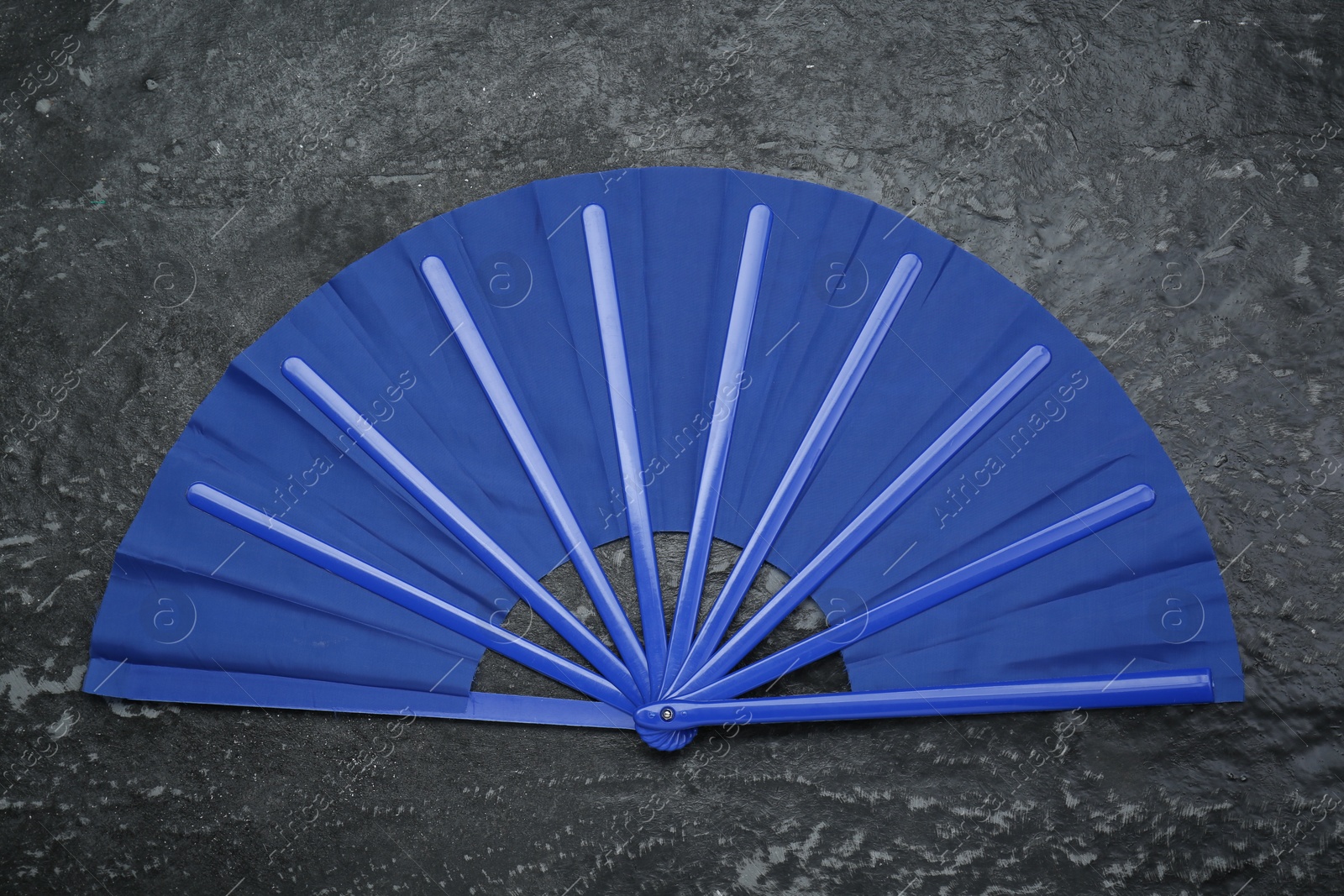 Photo of Bright blue hand fan on grey textured background, top view