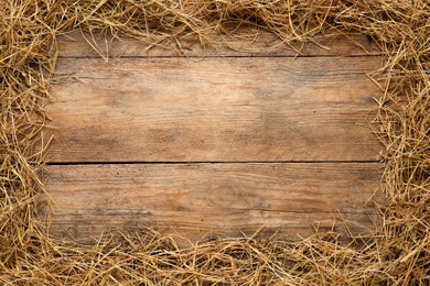 Photo of Frame made of dried hay on wooden background, top view. Space for text