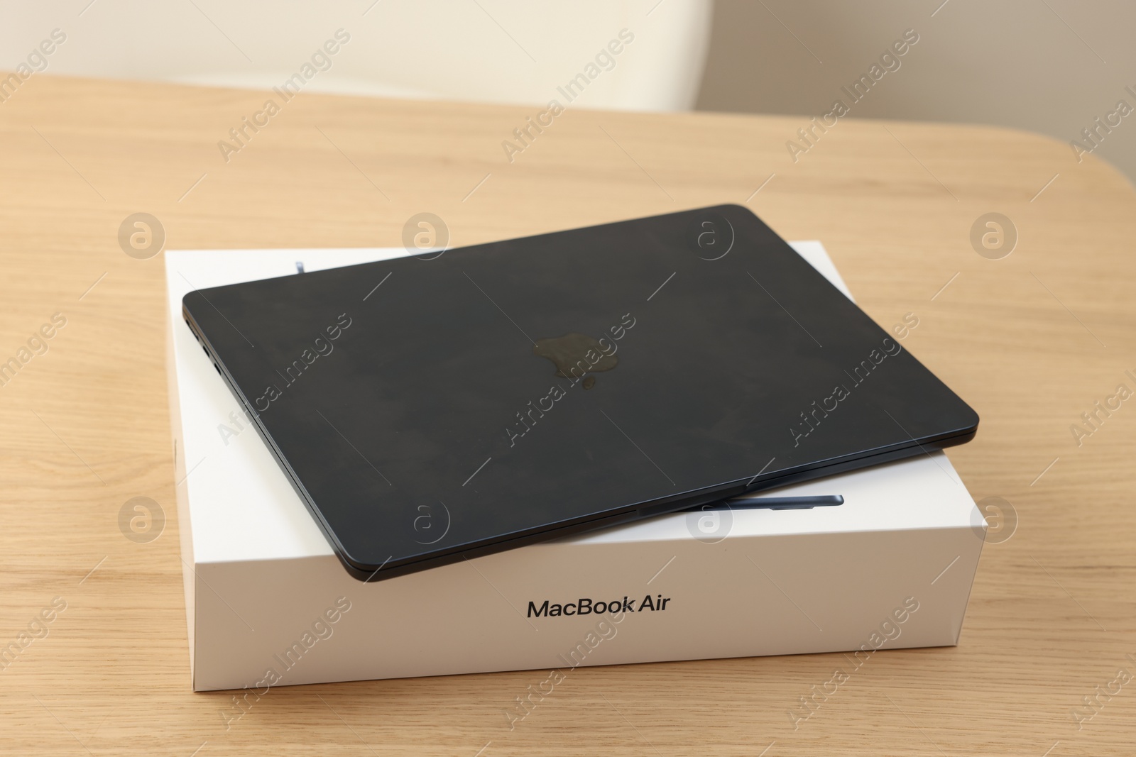 Photo of Leiden, Netherlands - October 6, 2023: Modern black MacBook Air and box on wooden table