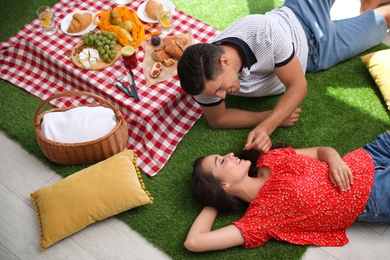 Photo of Happy couple imitating picnic at home, above view