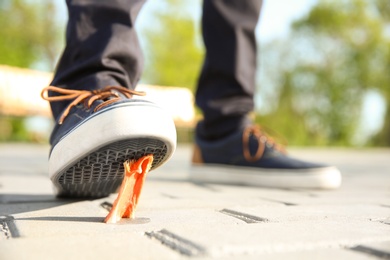 Photo of Man stepping in chewing gum on sidewalk. Concept of stickiness