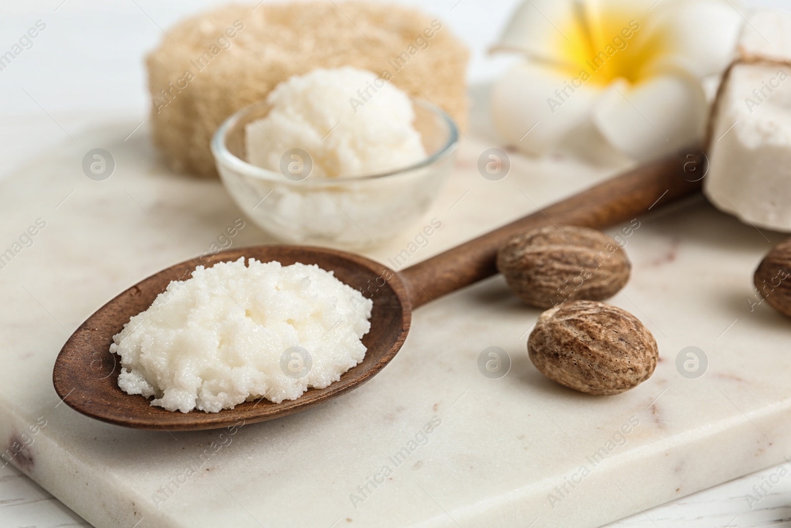 Photo of Spoon with Shea butter and nuts on marble board