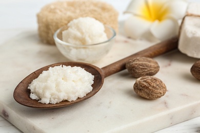 Photo of Spoon with Shea butter and nuts on marble board