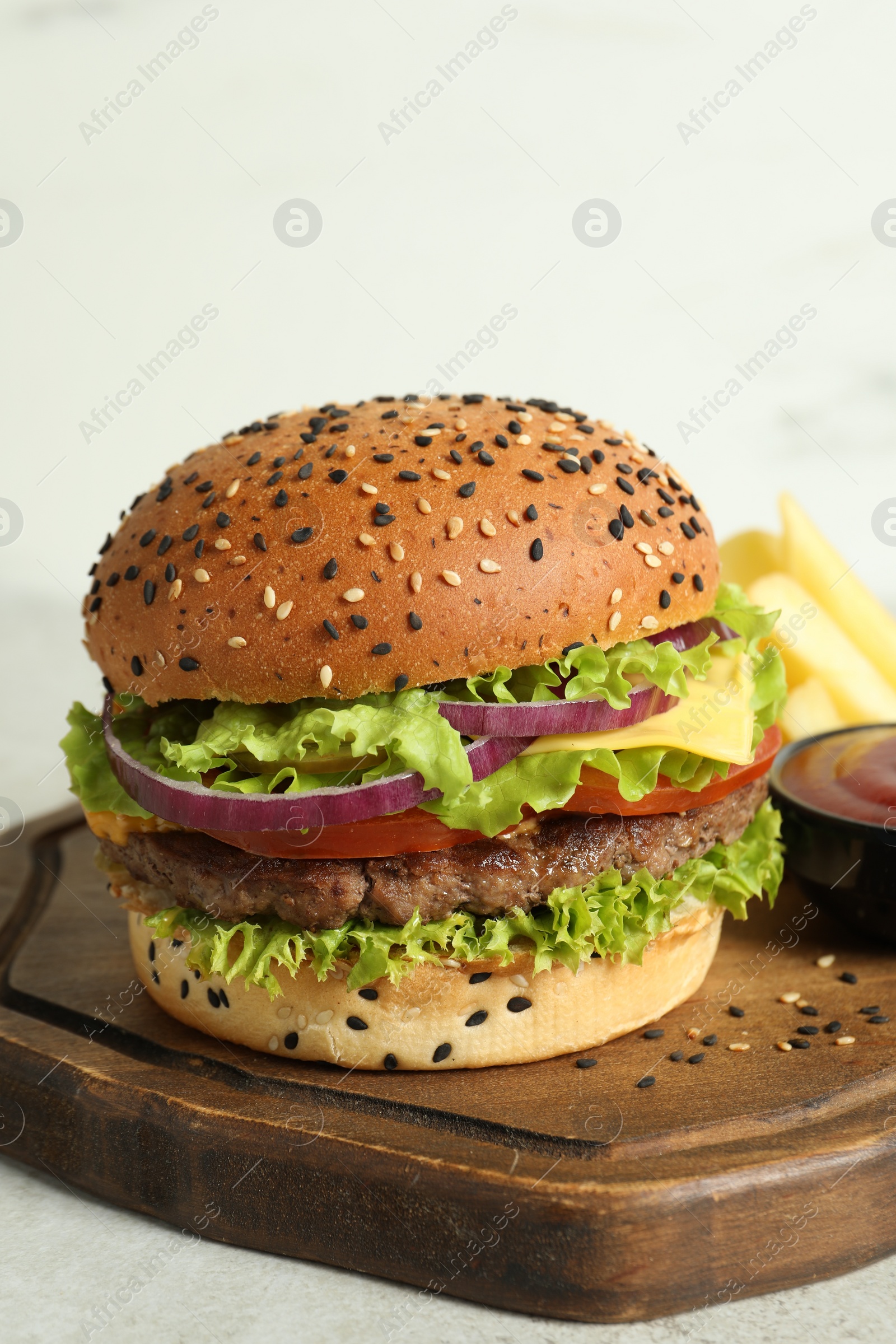 Burger with delicious patty, french fries and sauce on light table, closeup Photo of Burger with delicious patty, french fries and sauce on light table, closeup