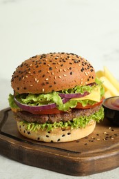 Photo of Burger with delicious patty, french fries and sauce on light table, closeup