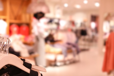 Photo of Rack with clothes on hangers in modern store, closeup