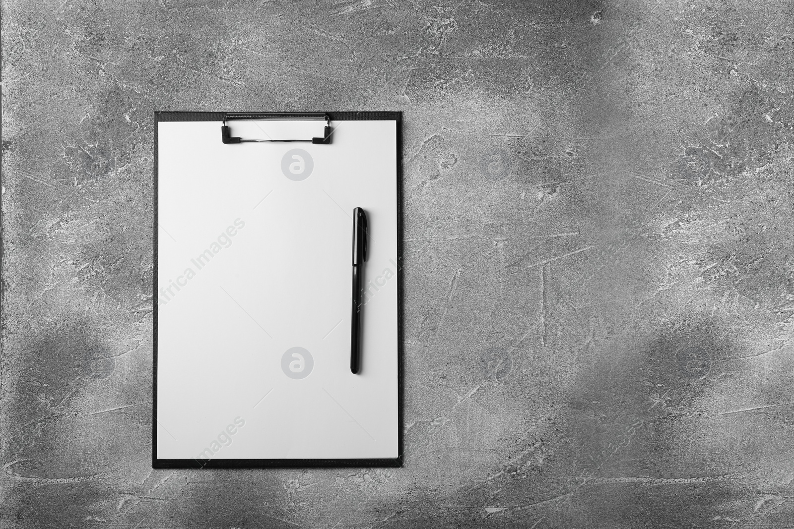 Photo of New clipboard with sheet of blank paper and pen on grey textured table, top view. Space for text