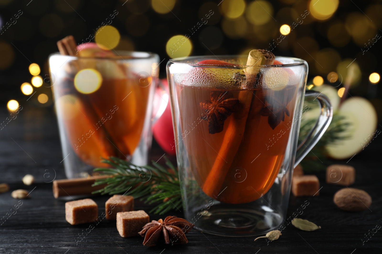 Photo of Aromatic hot mulled cider on black wooden table, closeup