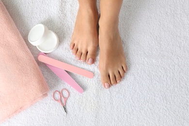 Top view of woman with beautiful feet and pedicure accessories on white towel, space for text. Spa treatment