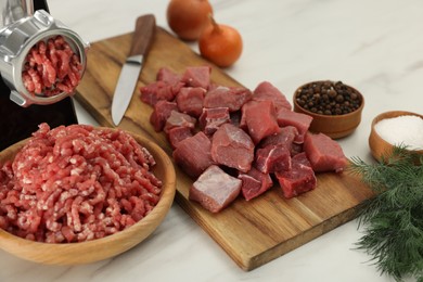 Electric meat grinder with beef and products on white marble table