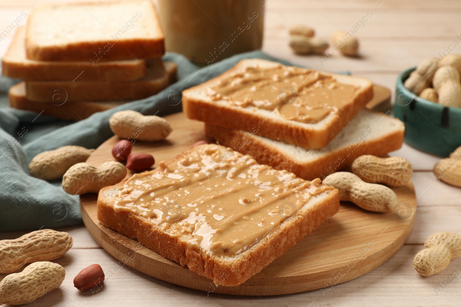 Photo of Delicious toasts with peanut butter and nuts on light wooden table, closeup