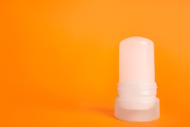 Photo of Natural crystal alum stick deodorant on orange background. Space for text