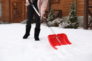 Young woman cleaning snow with shovel near her house