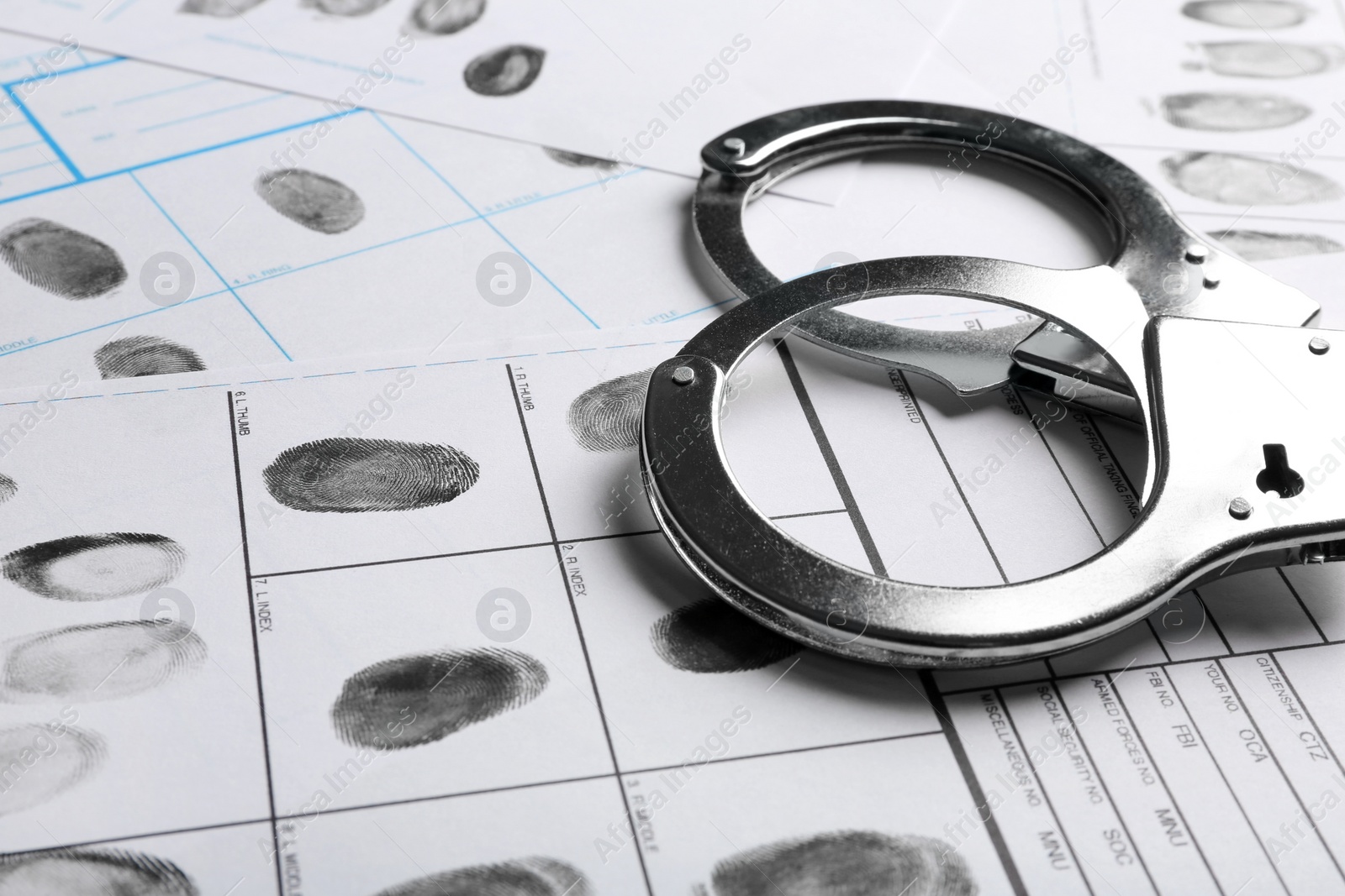 Photo of Handcuffs and fingerprint record sheets, closeup. Criminal investigation