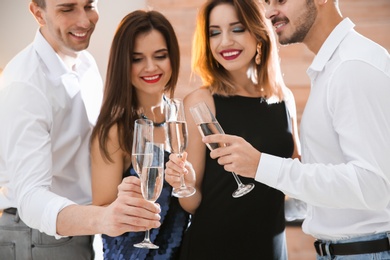 Friends clinking glasses with champagne at party indoors