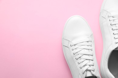 Photo of Pair of stylish white sneakers on pink background, top view. Space for text