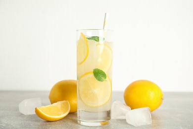 Photo of Cool freshly made lemonade, ice cubes and fruits on grey table