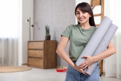 Image of Young woman with wallpaper rolls at home