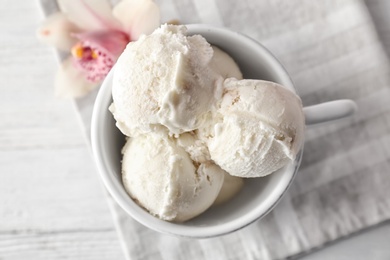 Photo of Cup with tasty vanilla ice cream on wooden background, top view