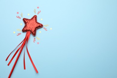 Photo of Beautiful red magic wand and confetti on light blue background, flat lay. Space for text