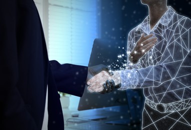 Businessman shaking hands with virtual partner in office, closeup