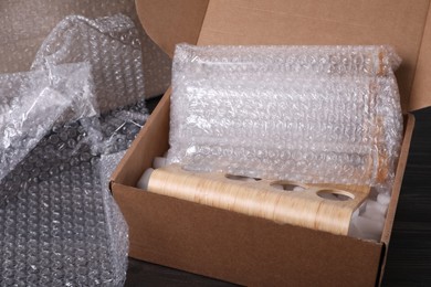 Photo of Test tubes in cardboard box and bubble wrap on dark wooden table