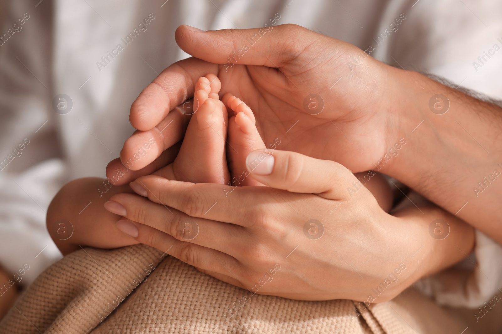 Photo of Mother and father holding their newborn baby, closeup view on feet. Lovely family