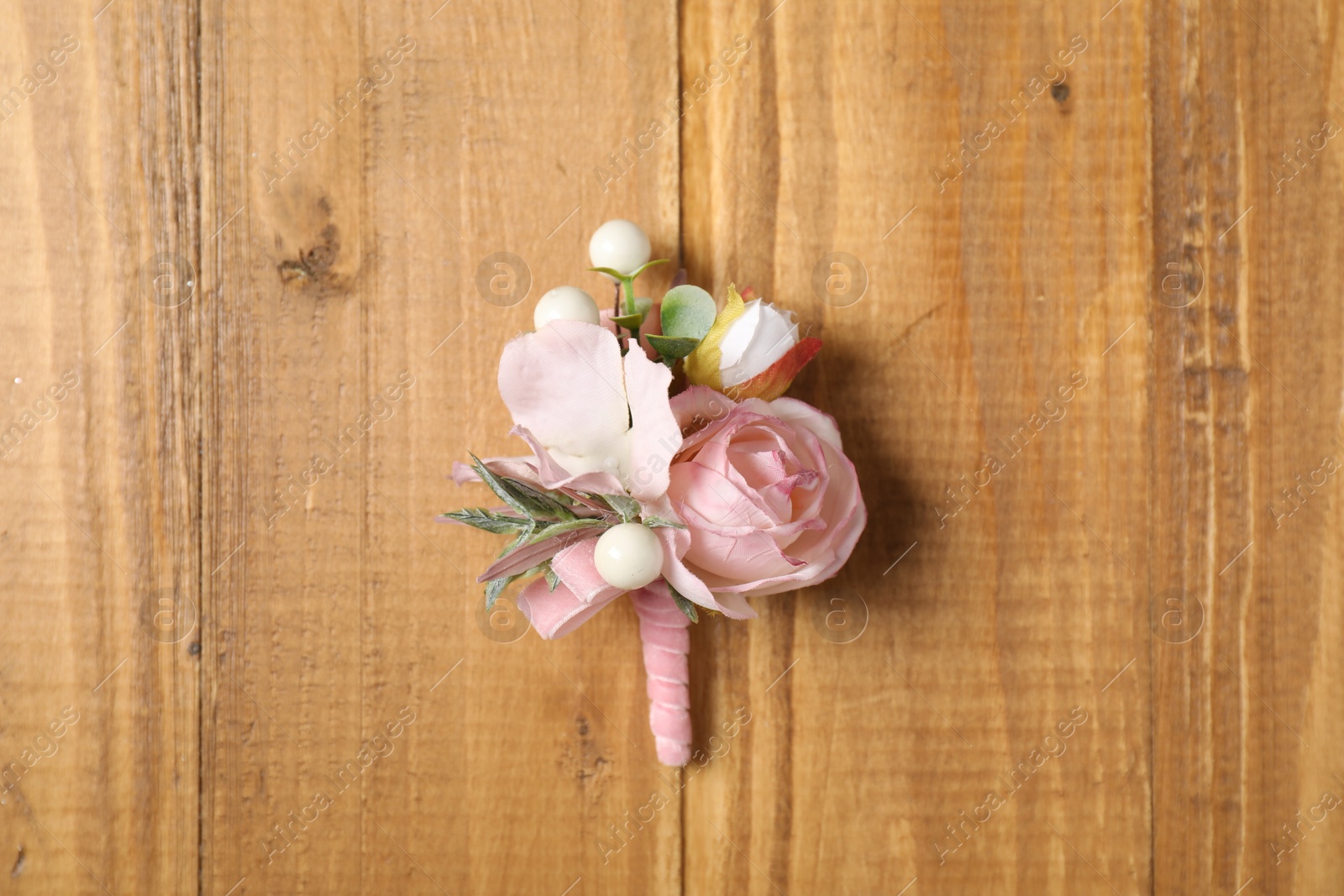 Photo of Stylish pink boutonniere on wooden table, top view