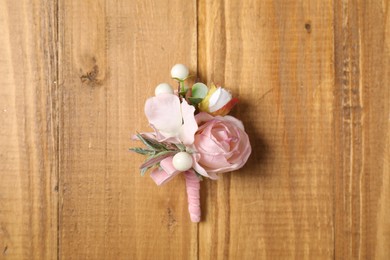 Stylish pink boutonniere on wooden table, top view