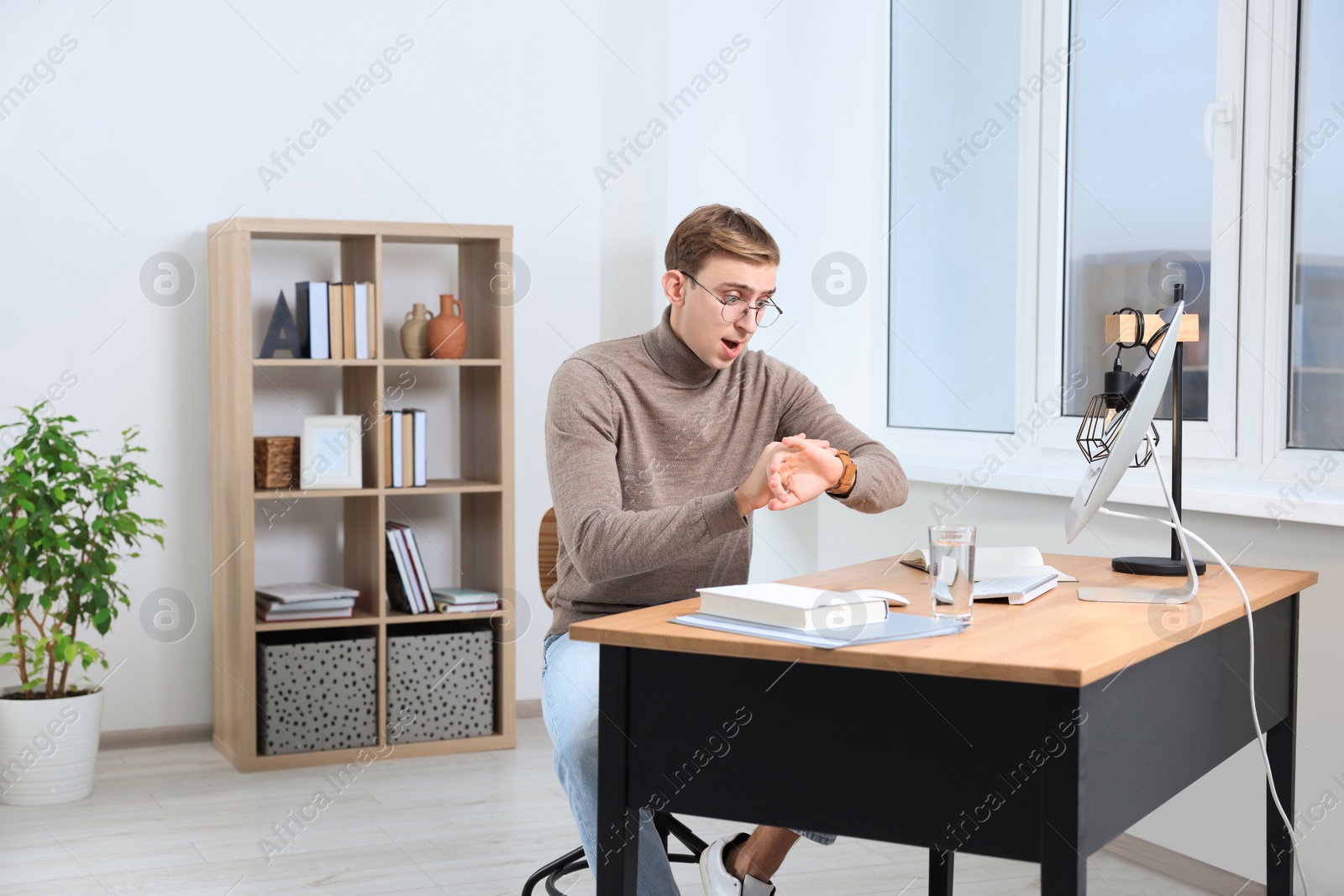 Photo of Emotional young man checking time in office. Being late
