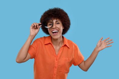 Photo of Excited woman looking through magnifier glass on light blue background