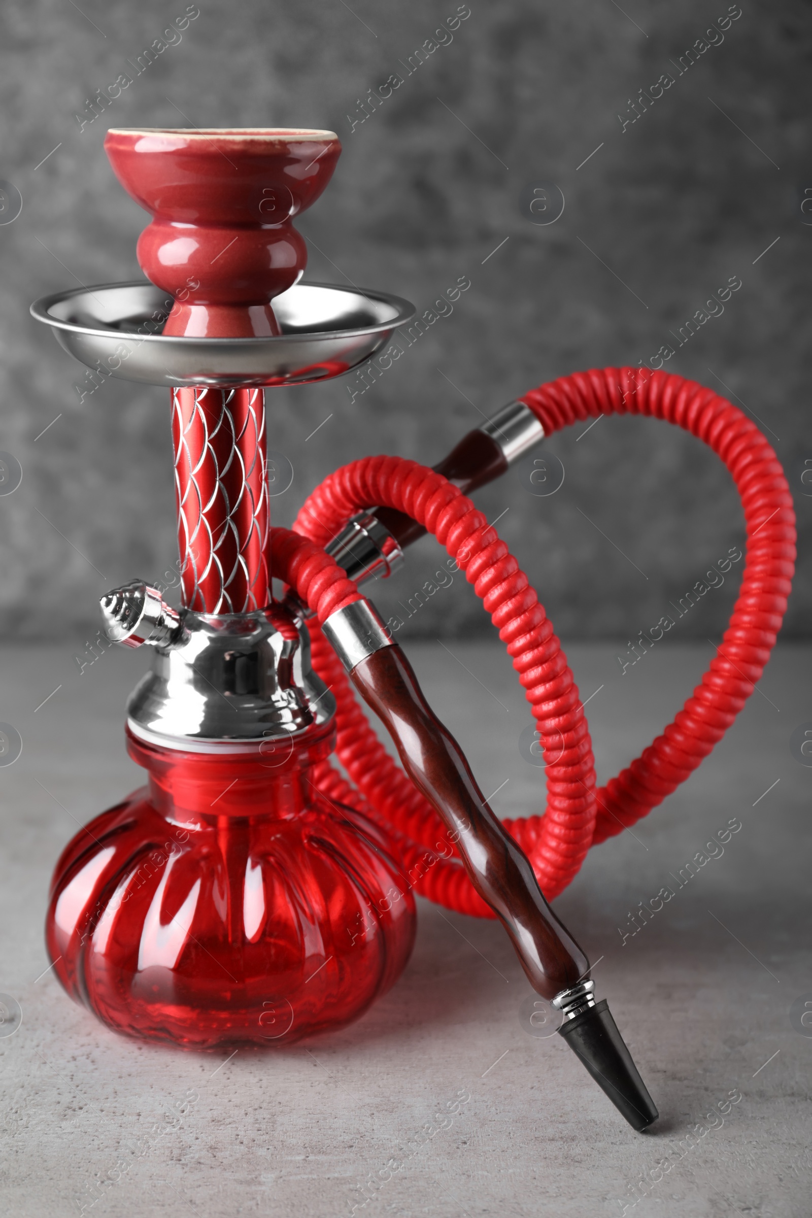 Photo of Modern red hookah on table against grey background