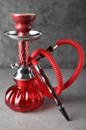 Photo of Modern red hookah on table against grey background