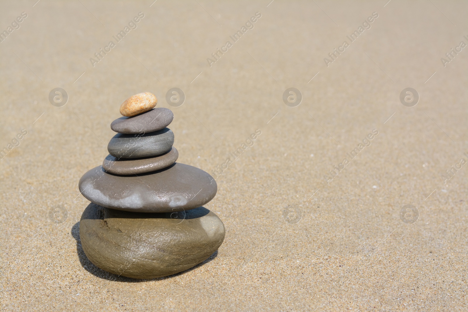 Photo of Stack of stones on sandy beach, space for text