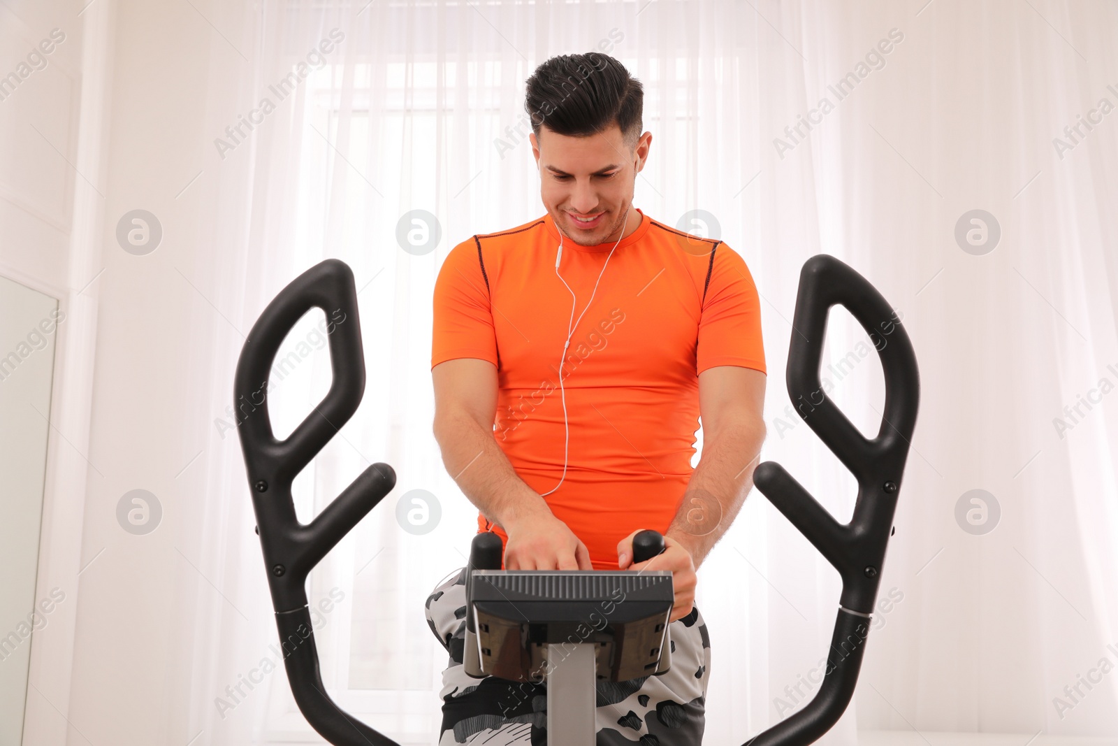 Photo of Man using modern elliptical machine at home