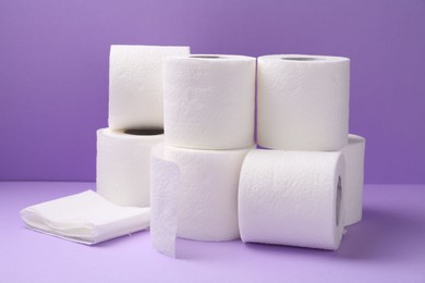 Photo of Soft toilet paper rolls on violet background