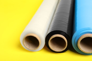 Photo of Rolls of different stretch wrap on yellow background, closeup