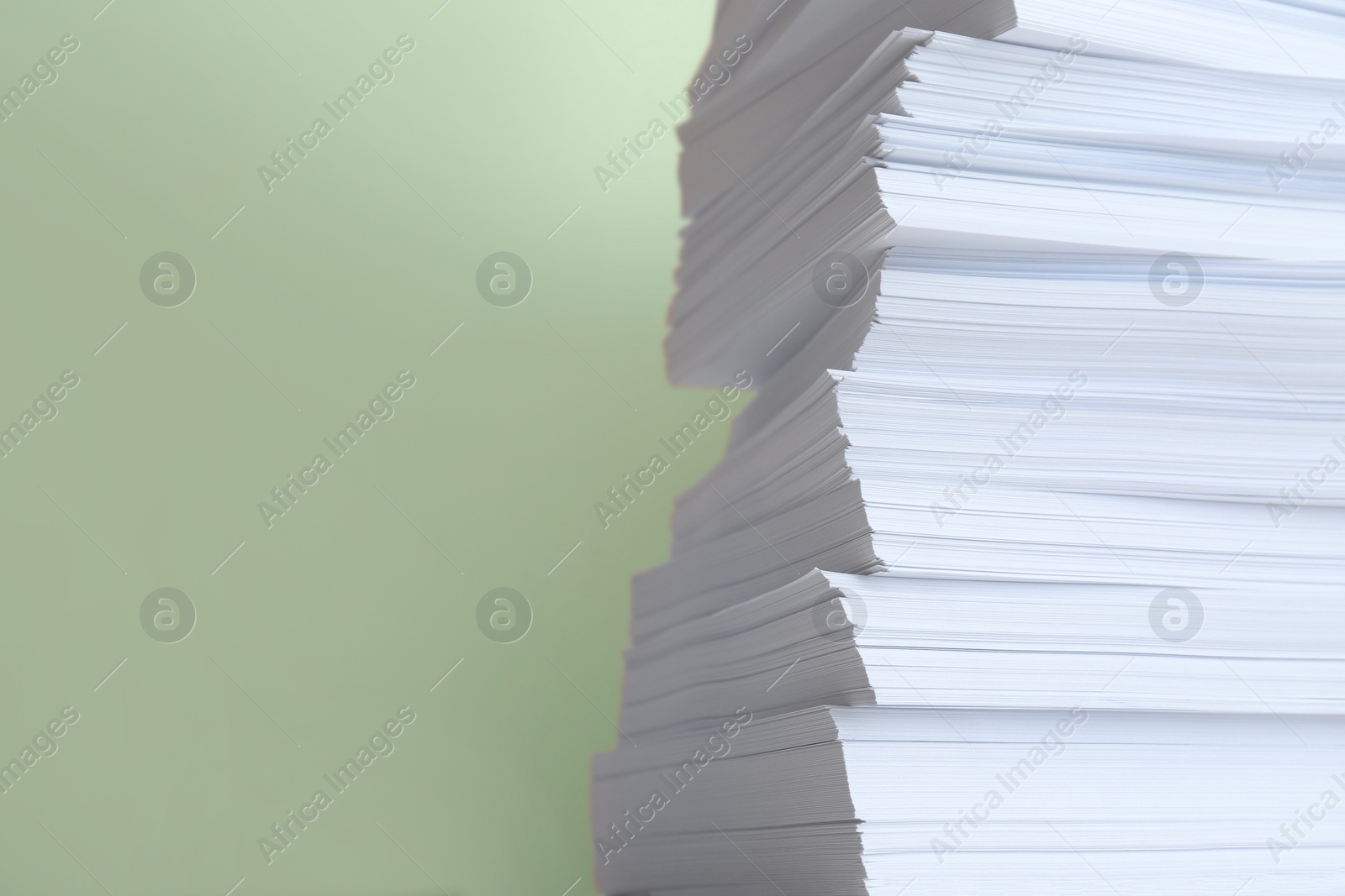 Photo of Stack of paper sheets on light green background, closeup. Space for text