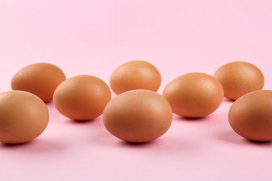 Raw brown chicken eggs on pink background